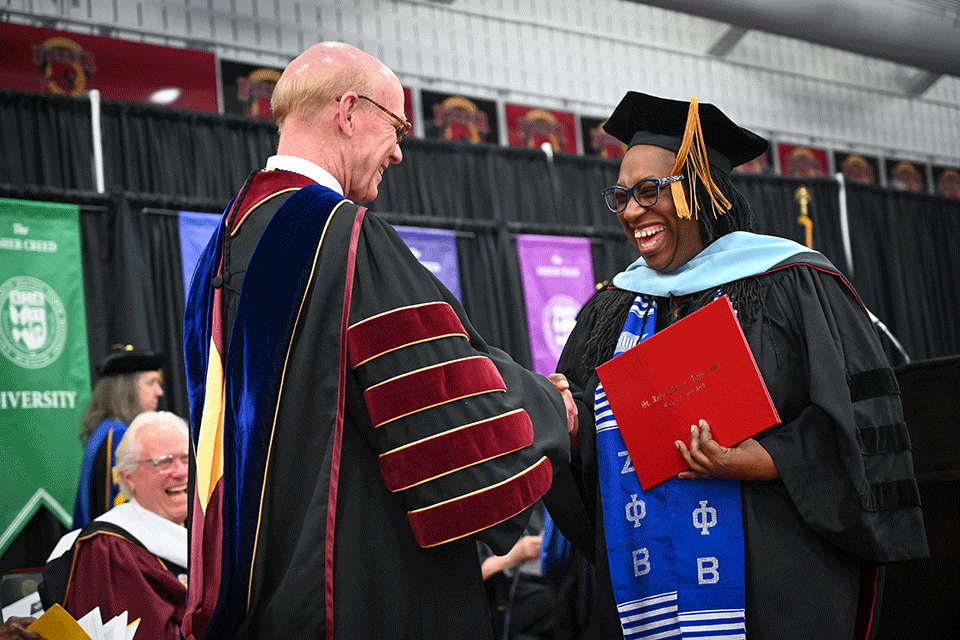 A graduate of the Ed.D. program shakes hands with President Rooney.